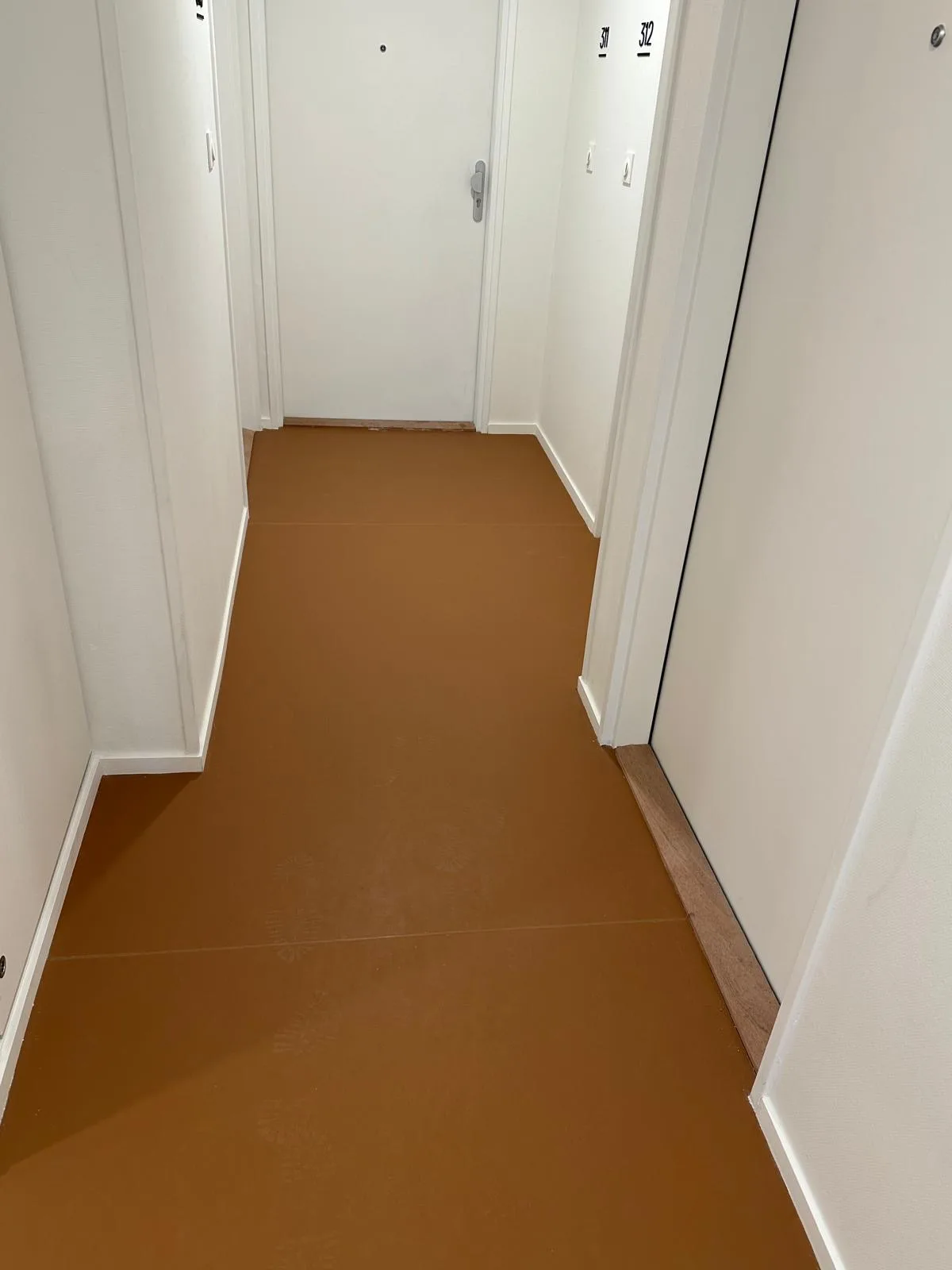 Circulation intérieure avec revêtement de sol ocre et murs blancs