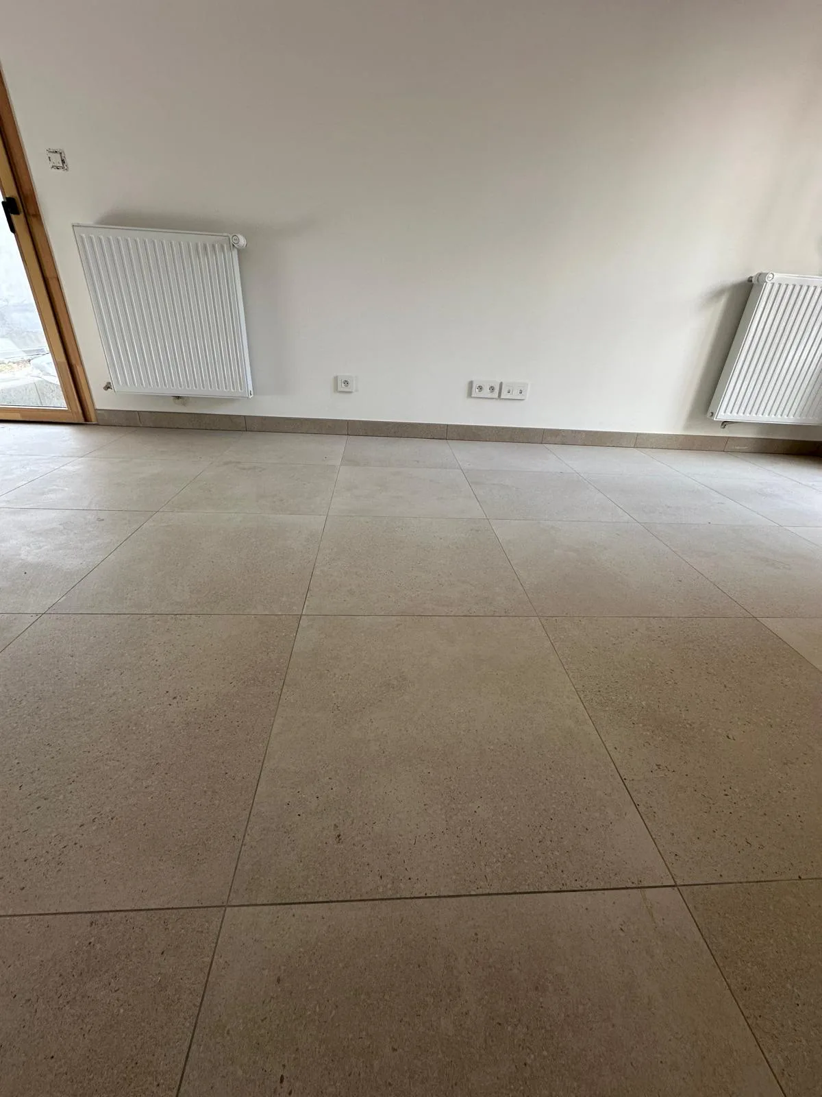 Carrelage de sol beige et plinthes carrelées dans une pièce aux murs blancs